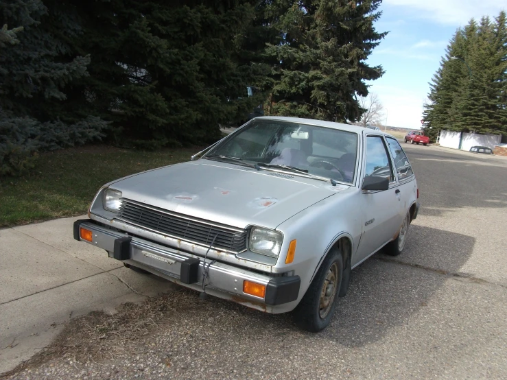 an old silver car parked on the side of the road