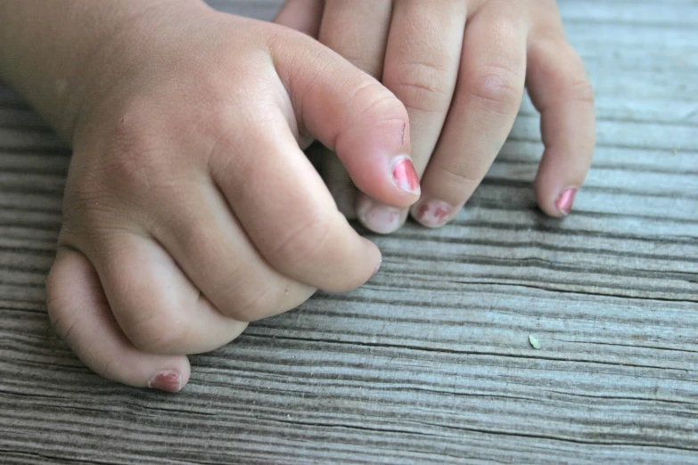 hands with pink nail designs on them are resting on a table