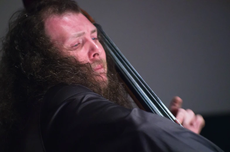 a man with long hair holds onto his cello