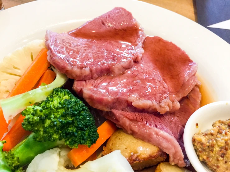 a white plate topped with meat, vegetables and sauce