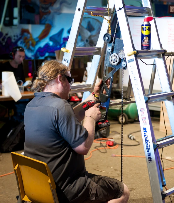 a man sitting on a chair working on a ladder