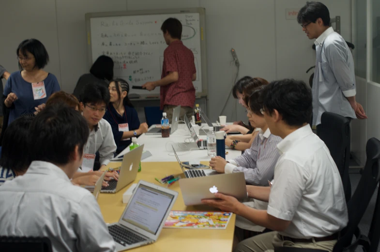 a group of students sitting around a table and working on their laptops