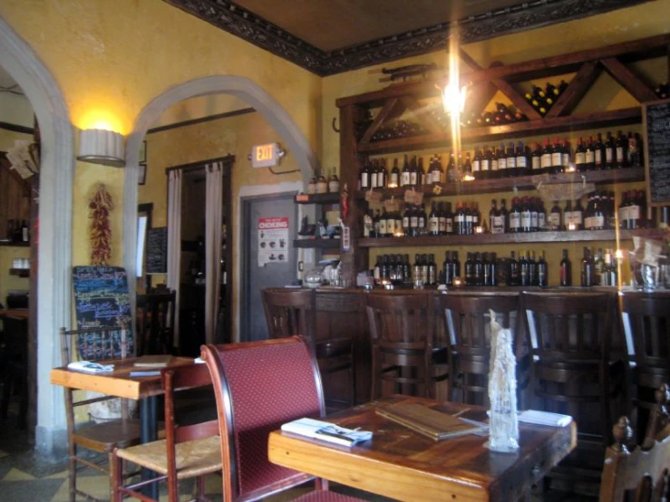 a dining area with wooden tables and bar and liquor bottles on the walls