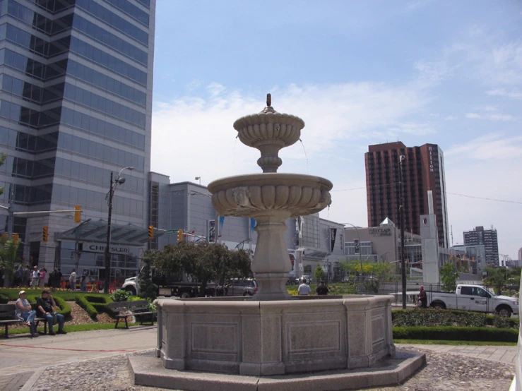 there is a fountain in the middle of a park with people walking around it