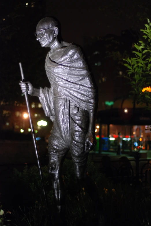 a statue stands next to the grass at night