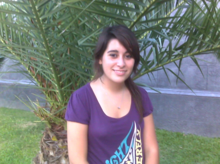 a woman standing next to a palm tree