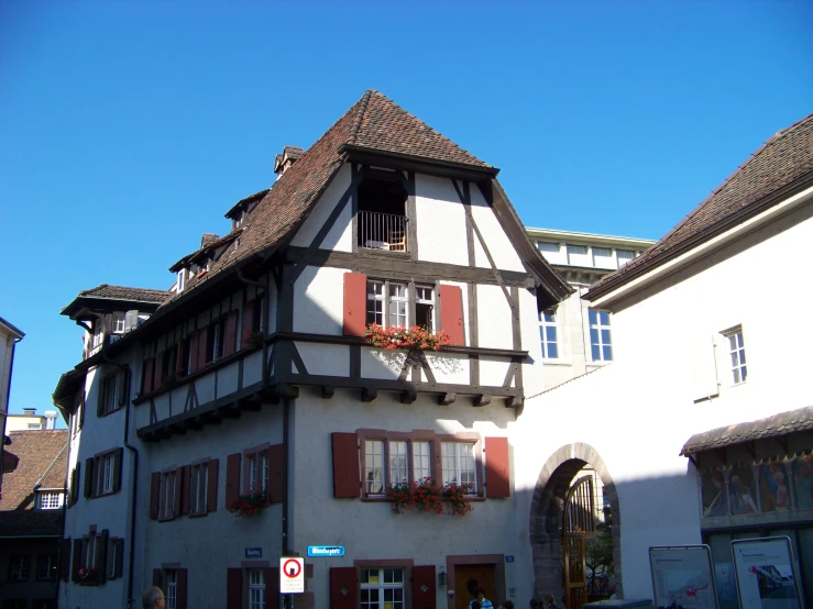 a white and red building with brown trim, red shutters, and two floors