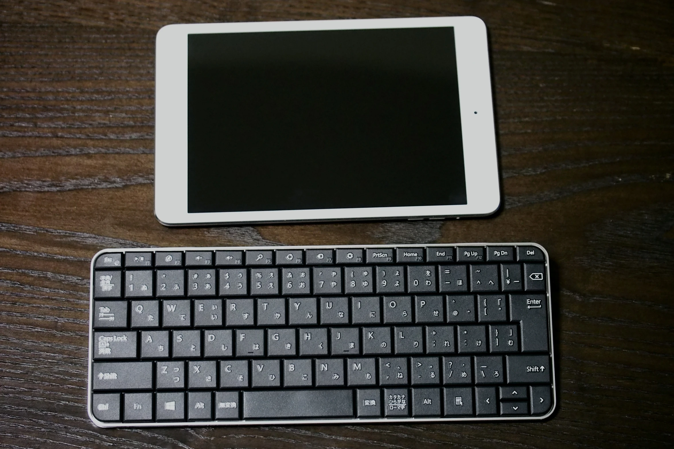 the keyboard is next to an ipad on a wooden surface