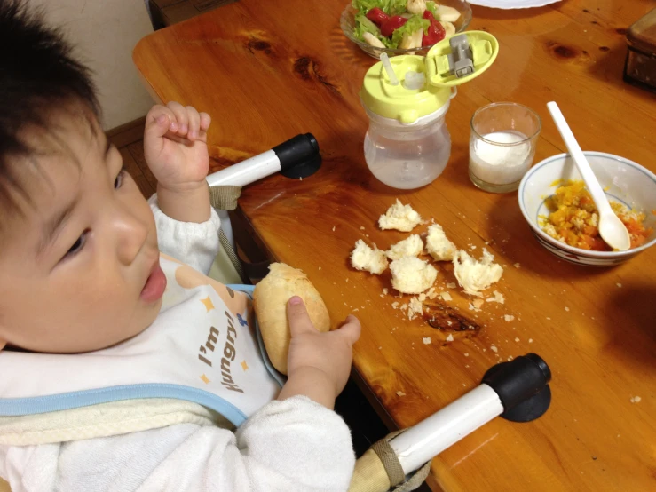 a child standing at the table eating a sandwich