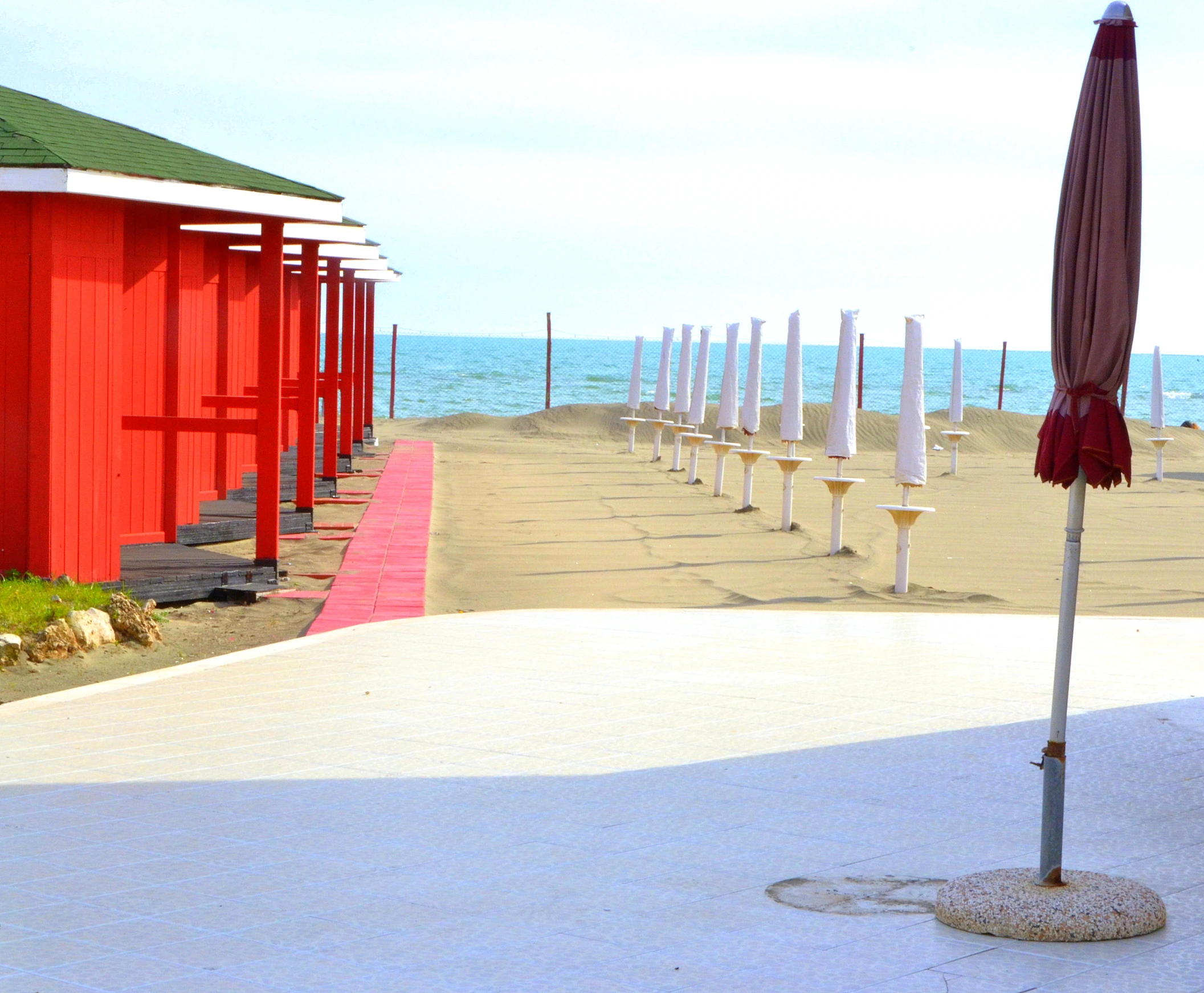 several rows of red and white umbrellas next to the ocean