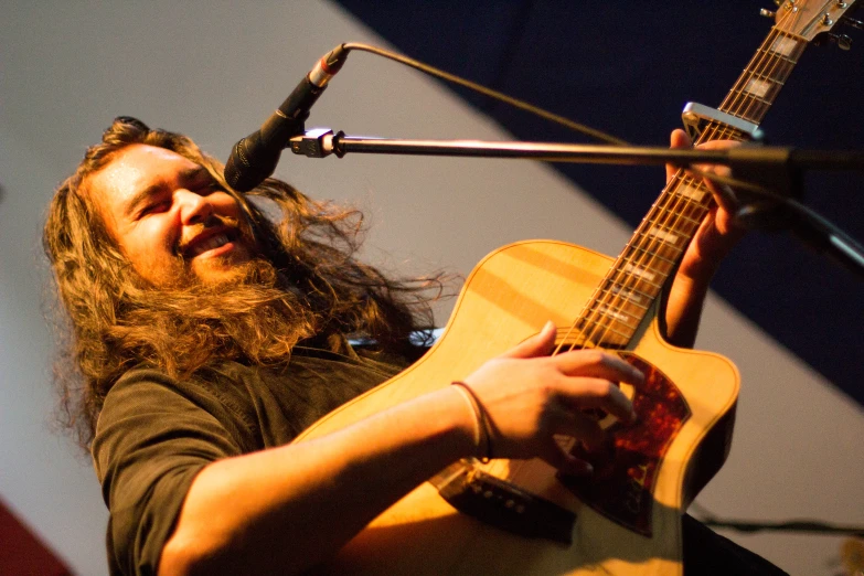 the man is playing a guitar while wearing earphones