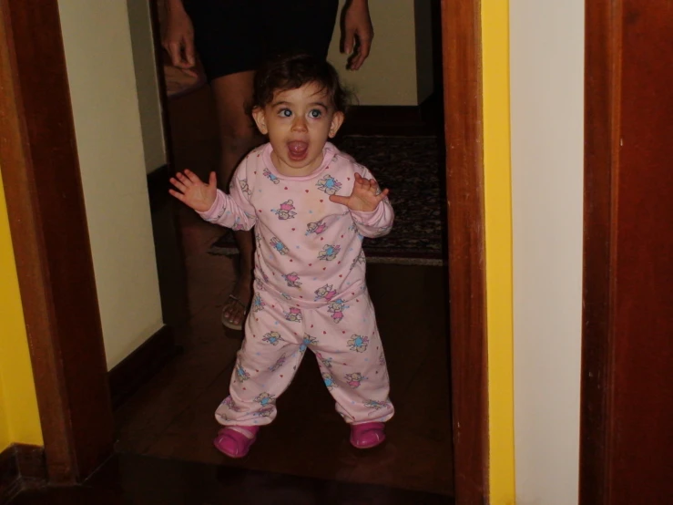 little girl sticking her tongue out standing in the doorway