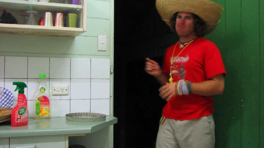 a man wearing a straw hat stands in the bathroom