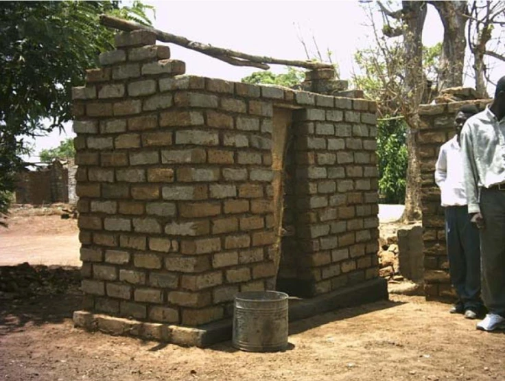 a group of men standing near brick walls in a village