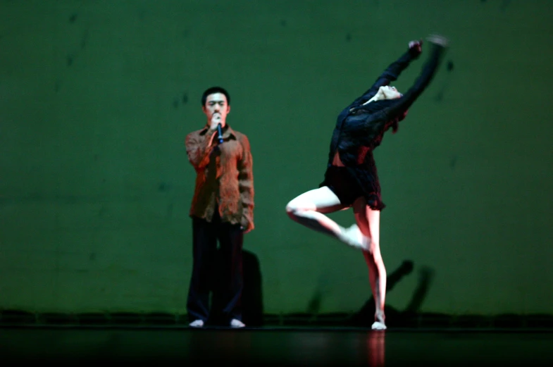 a man on stage with a woman in a suit behind him