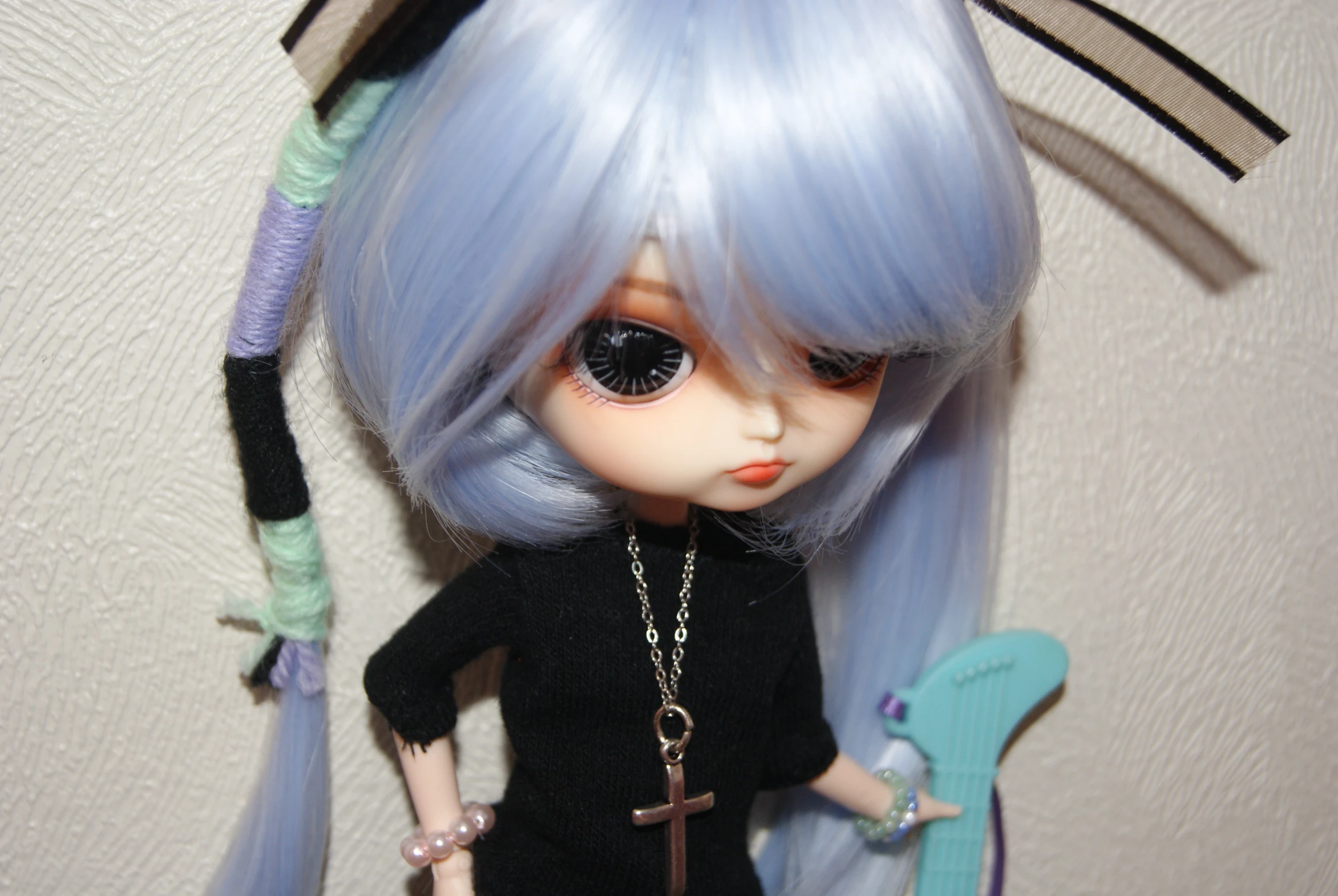 a doll with blue hair, wearing a black shirt and necklace