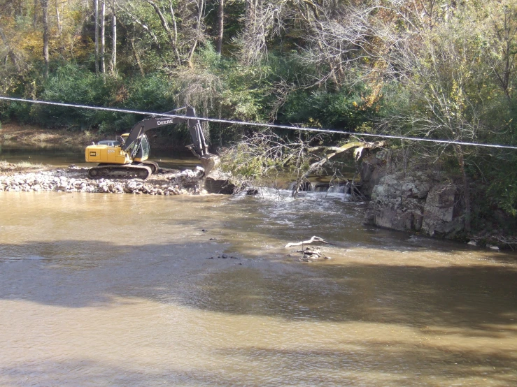 a yellow bulldozer parked next to a river