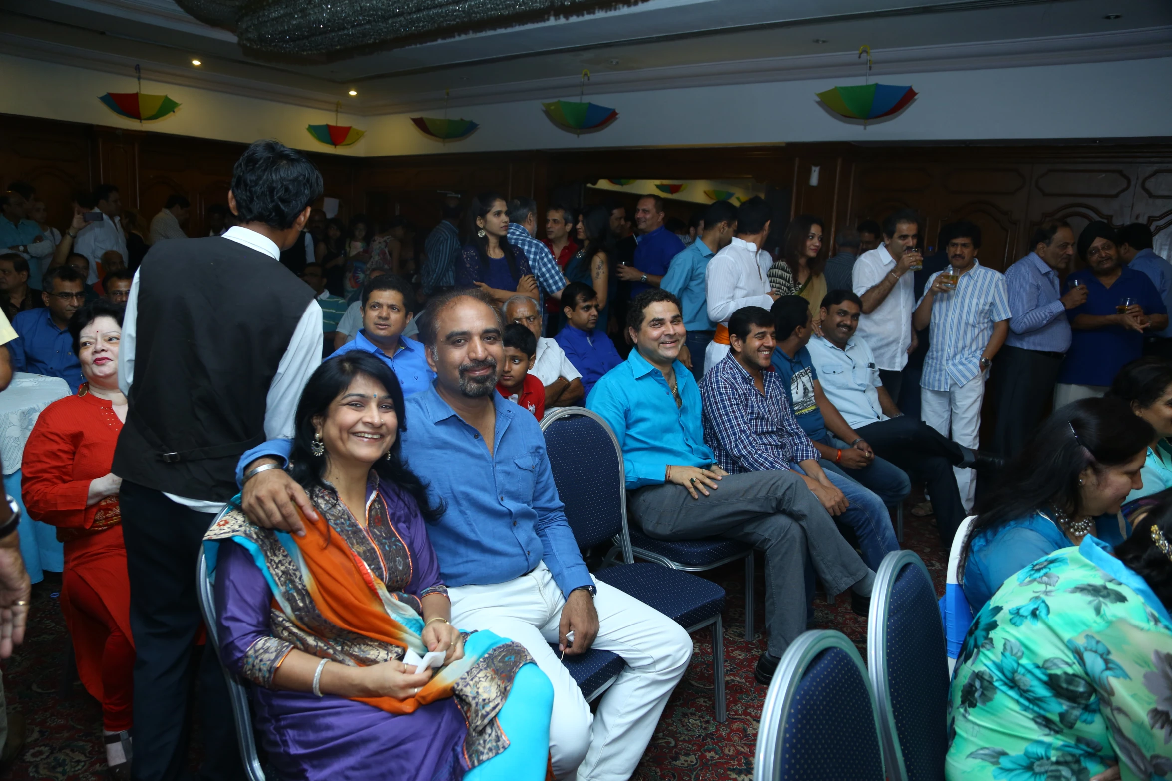 group of people in blue, purple, orange and green outfits seated on the chairs