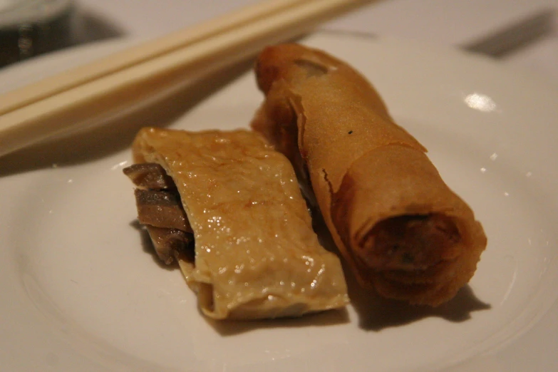 a piece of meat covered and rolled in a pastry sitting on a plate next to chopsticks