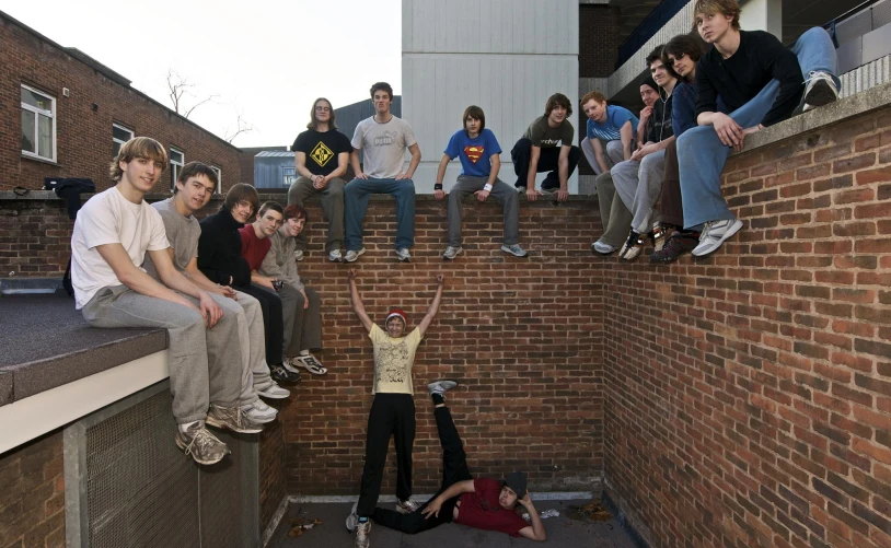 a group of people sitting on a brick wall in front of a man