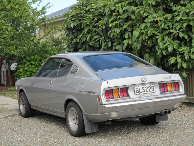 a gray sports car parked next to some trees