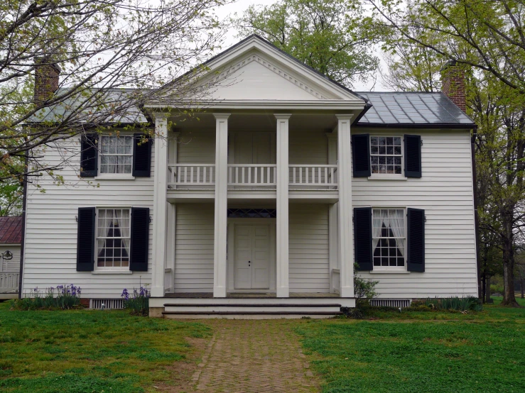 a house with black shutters and green grass in front