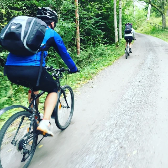 three men riding bikes down a narrow rural road