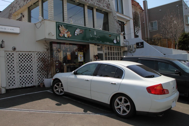 a white car parked outside a store with people in the window