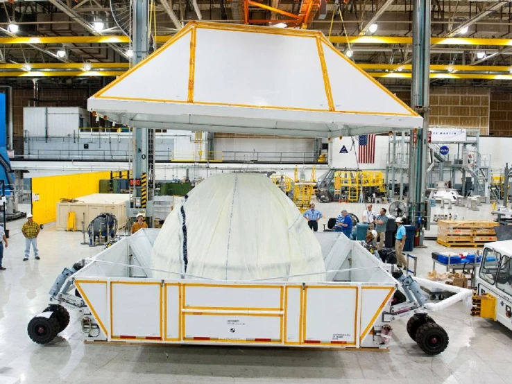 workers inside an assembly factory inspecting and working on a car