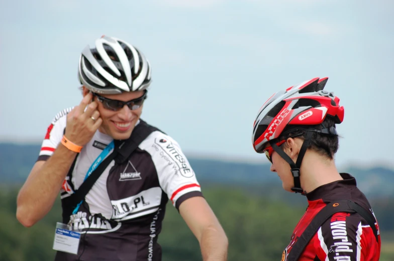 the two men wearing helmets talking on their phones