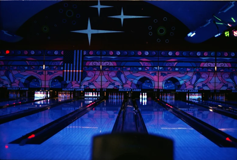 a bowling alley that has blue lights and a mural on the wall