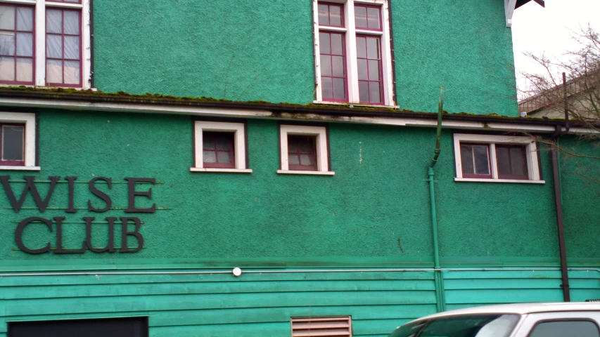 a green building with several windows and a few cars parked in front