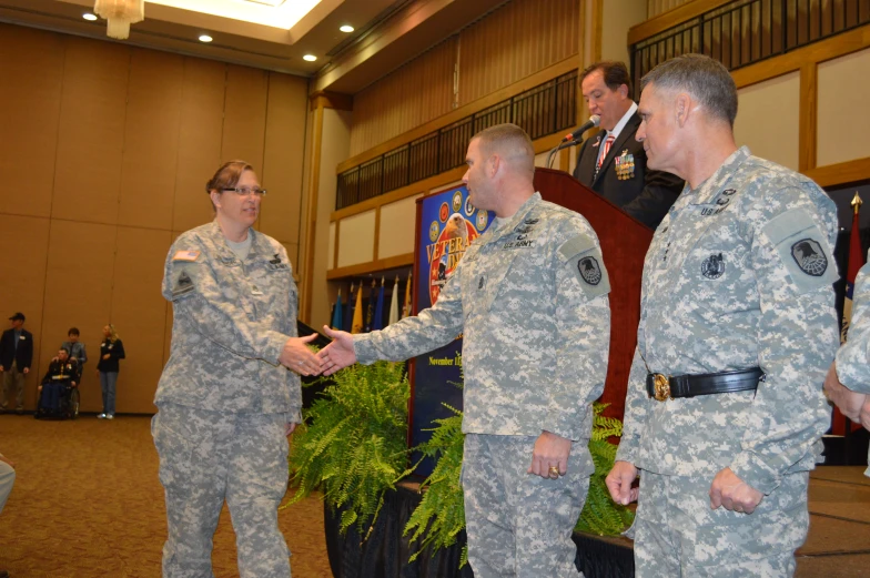 a man in a uniform shakes hands with two other men