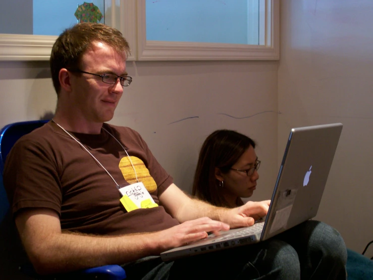 a man and woman with badges on their shirts sitting on a laptop