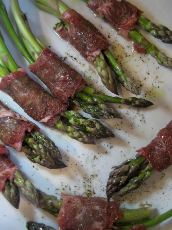 green asparagus and raw meat on top of a plate