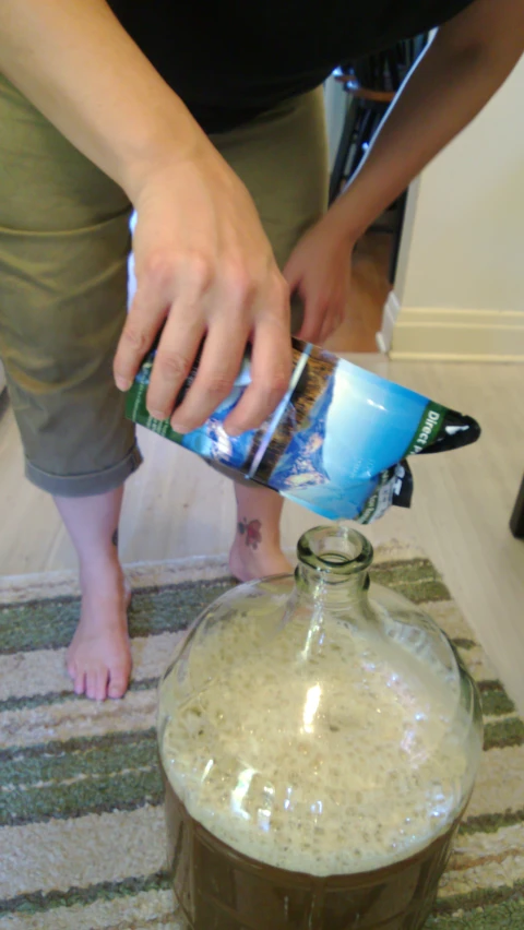 a person pours a juice into a container with a beverage inside