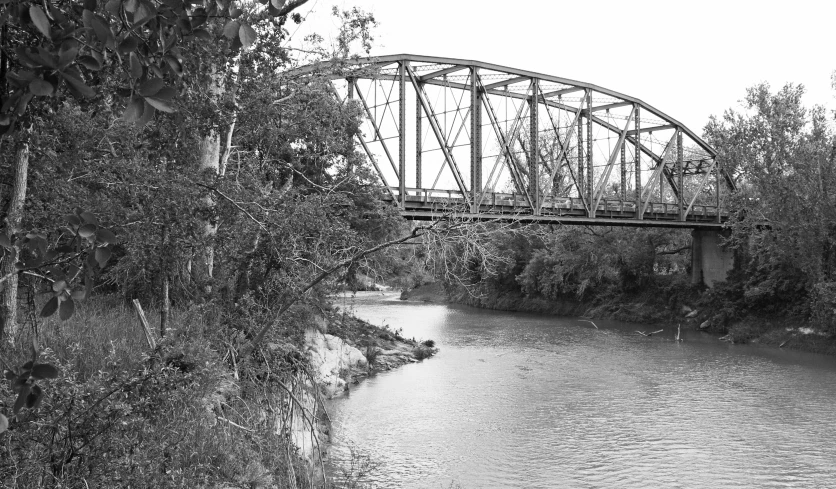 a large old bridge crosses a river in black and white