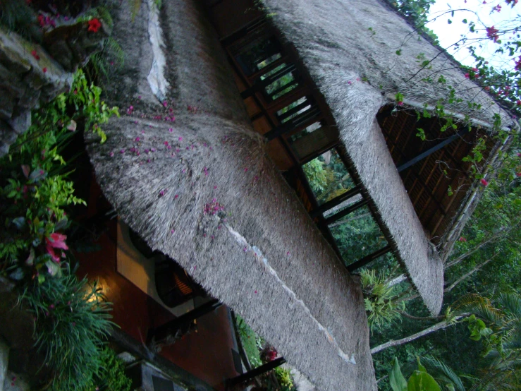 a stone building with a straw roof sits among the flowers