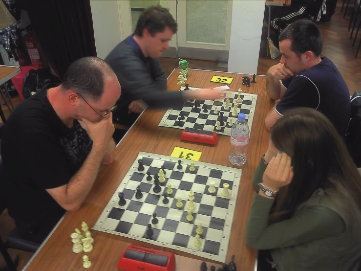 three people play a game of chess in a restaurant