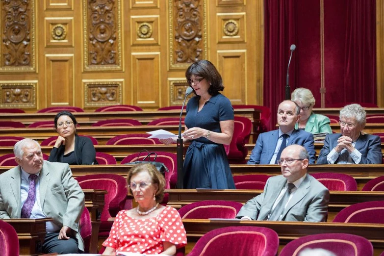 several people sitting in rows of empty wooden seats