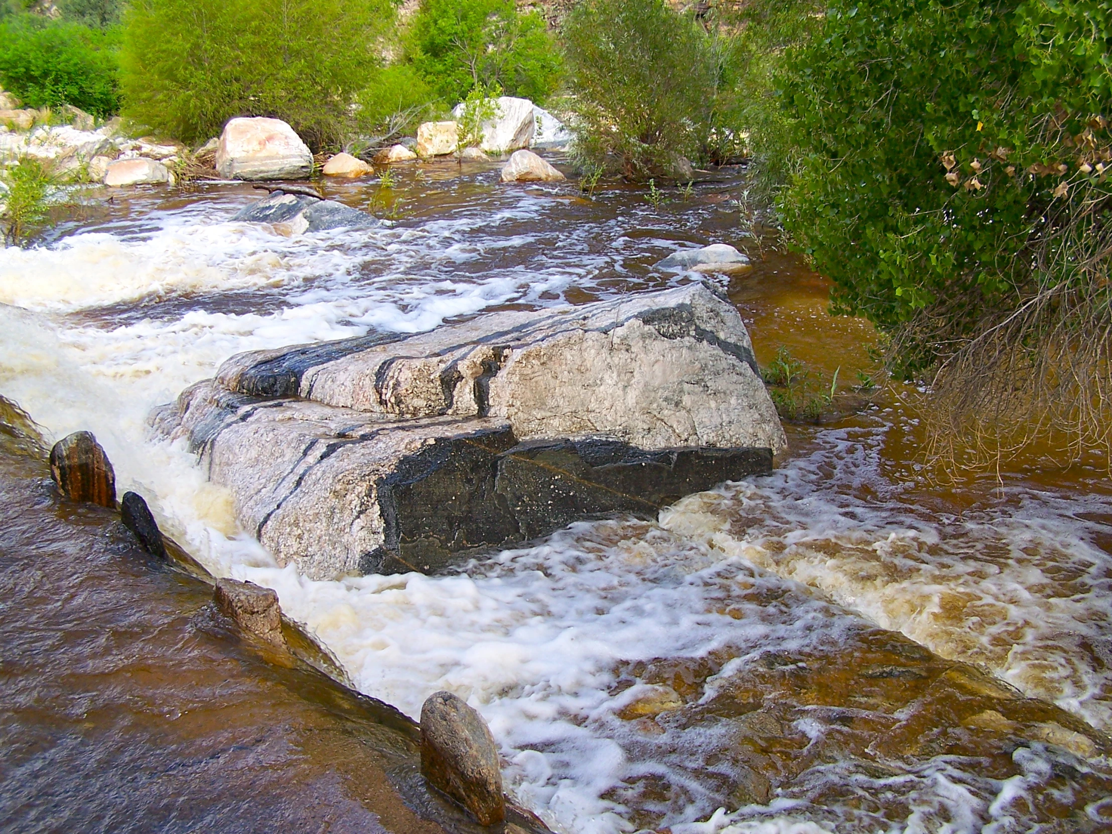 a river with rocks, rocks and water rushing up the sides