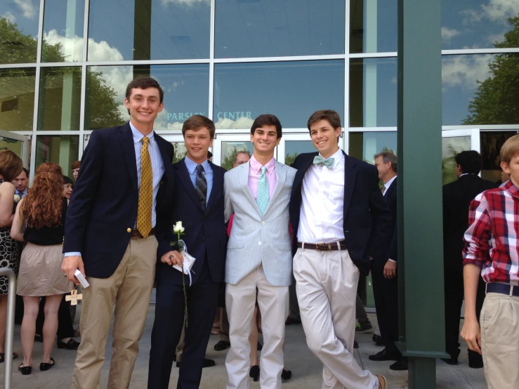 four young men wearing ties are standing outside