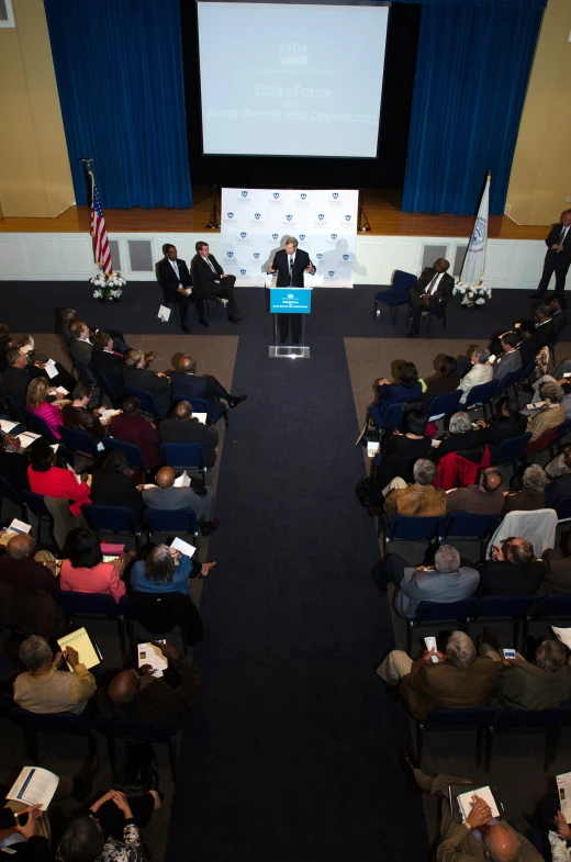 several people at an event sit in a hall and listen