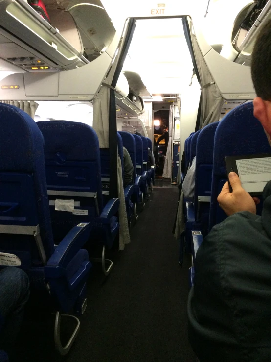 a person sitting on a plane with his cell phone in their hand