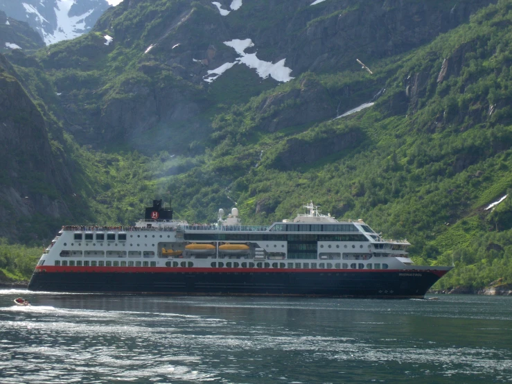 a large boat floating in the ocean between mountains