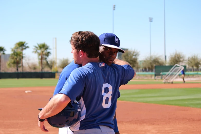 two baseball players hugging each other on the baseball field