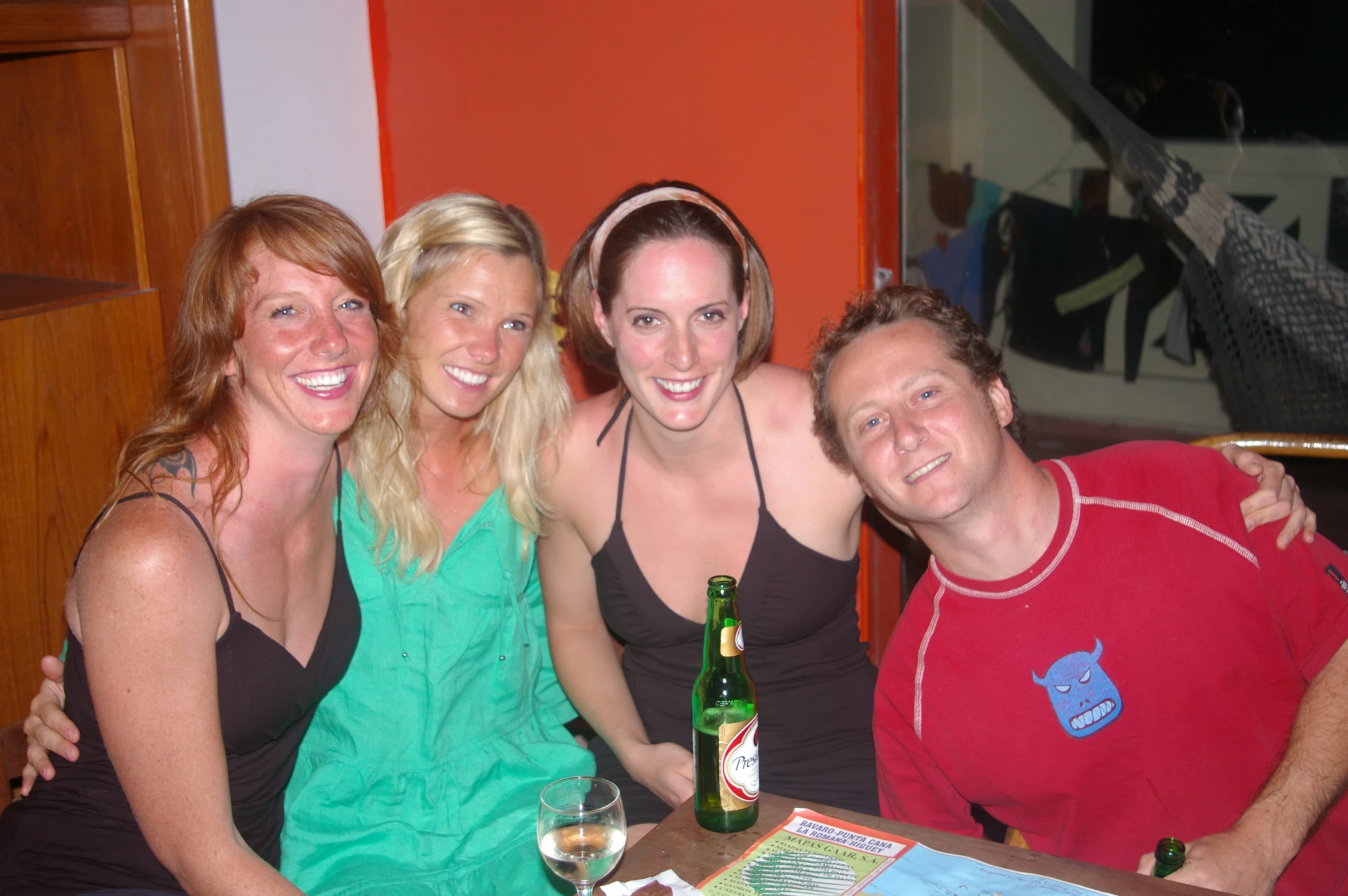 four smiling people pose in front of a beer bottle