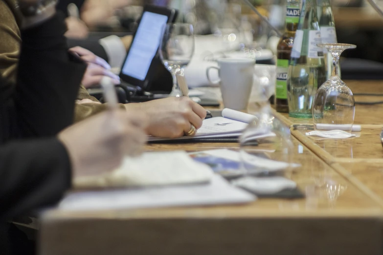 two people are typing on their laptops at a long table