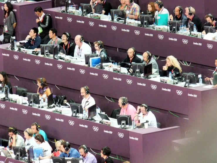 several people in an arena sit at desks