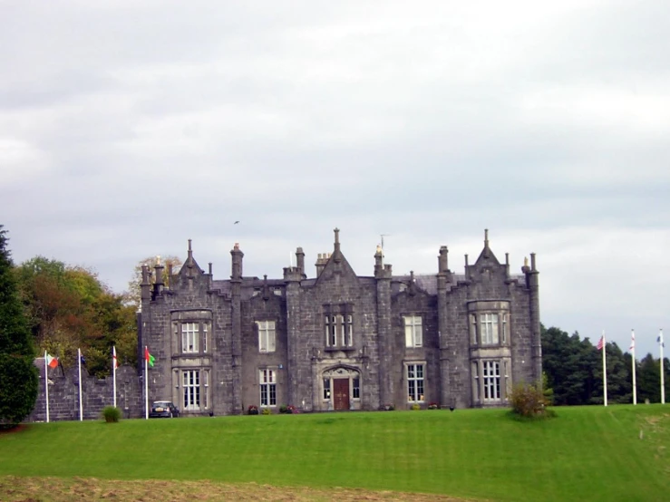 the large grey castle with white windows sits on a green hill